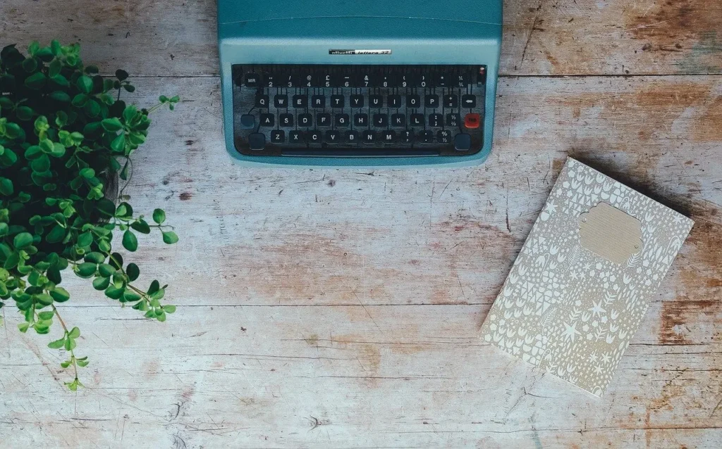 Vintage typewriter on a worn wooden desk with a notebook to the side